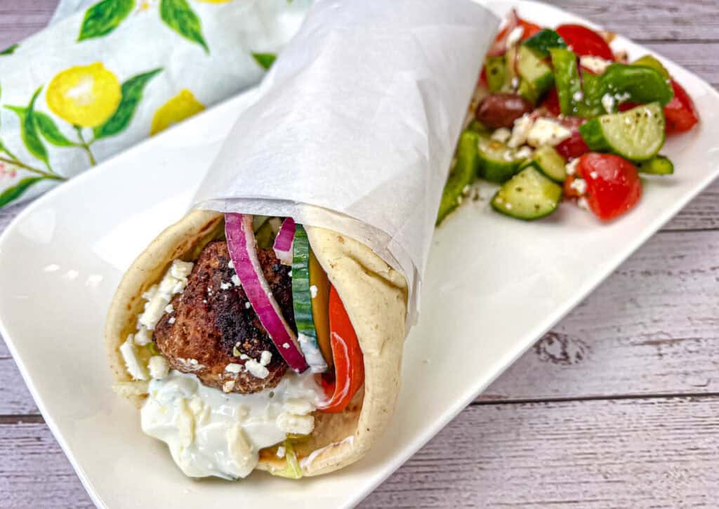 Greek Meatball Pita Sandwich served on a white rectangular plate.