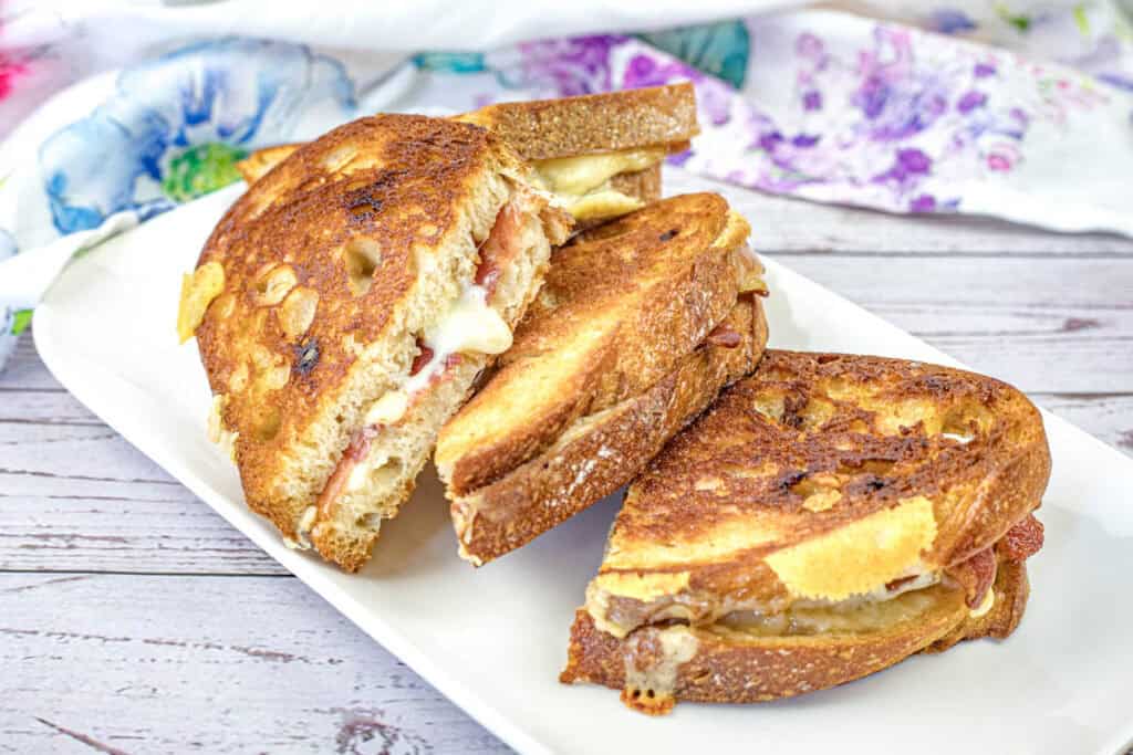 A plate with halves of Bacon Grilled Cheese Sandwiches with Hot Honey Butter.