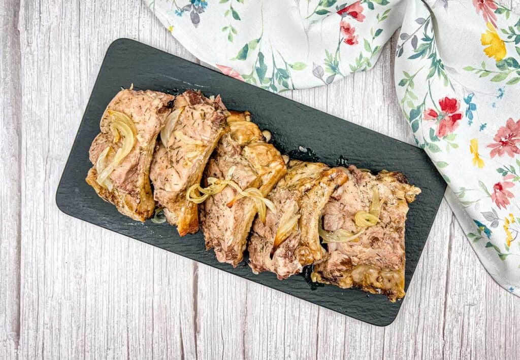 Top-down of oven baked ribs on a slate plate.