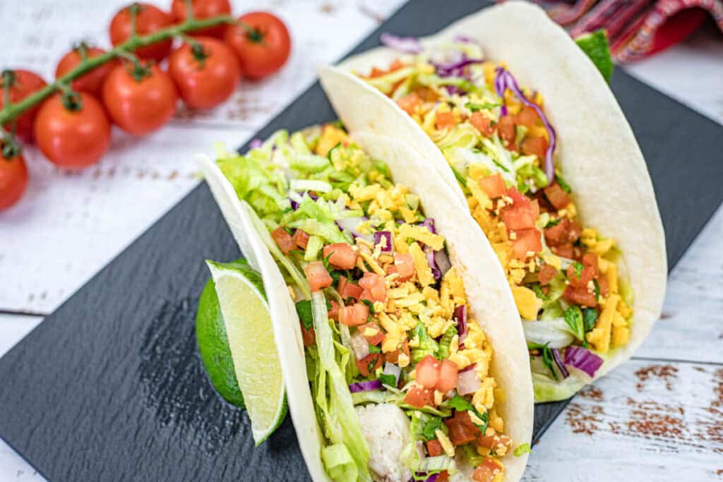 Two pieces of Copycat Taco Bell Cantina Chicken Tacos served on a black slate plate.