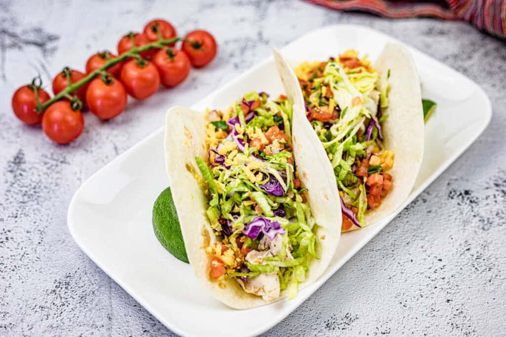 Two pieces of Copycat Taco Bell Cantina Chicken Tacos on a white rectangular plate.