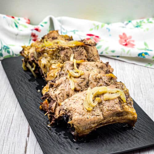 Oven baked ribs on a black slate plate.