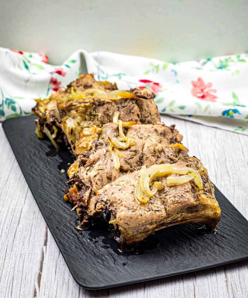 Oven baked ribs on a black slate plate.