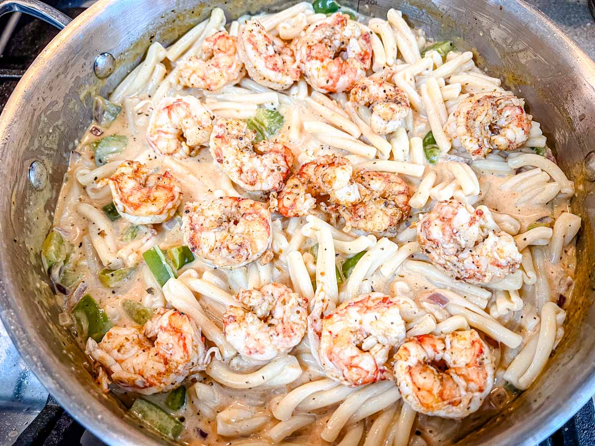 Toss the cooked pasta into the skillet with the creamy sauce and vegetables.