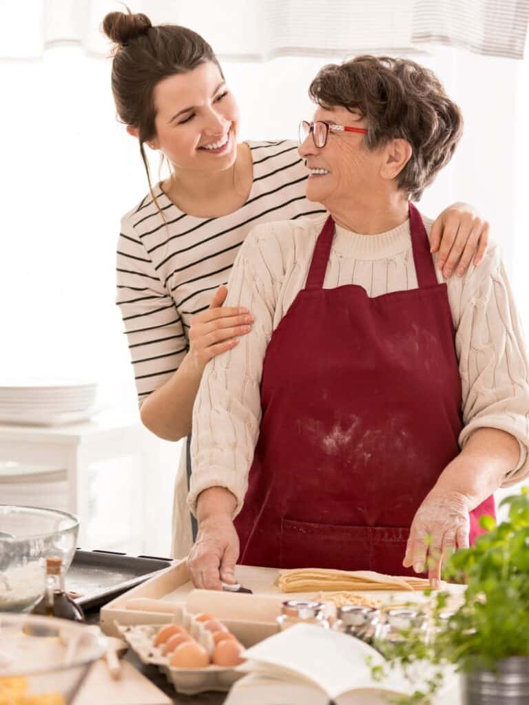 Grandmother and granddaughter looking at each other while preparing ingredients.