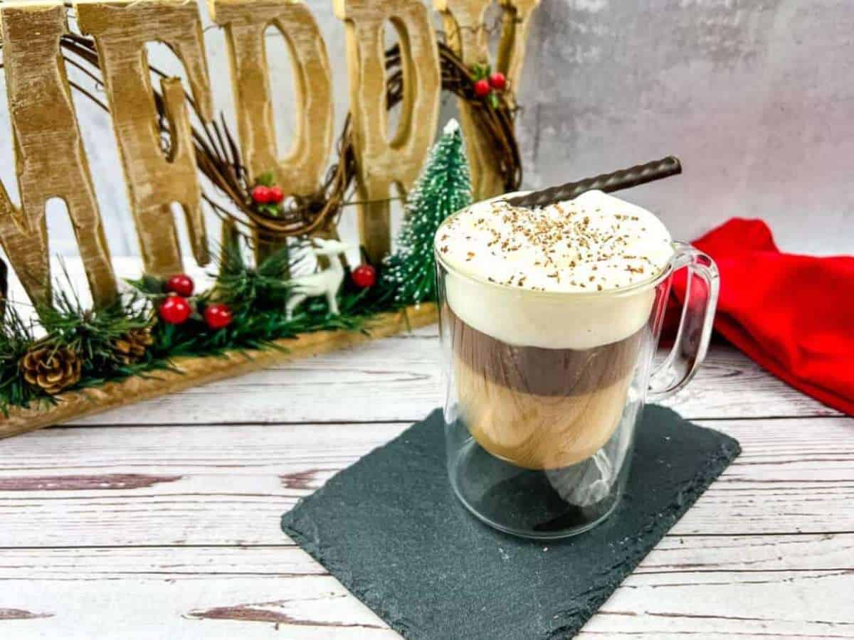 A canadian coffee with a whipped cream and cinnamon sticks.