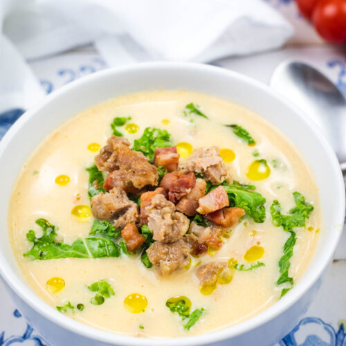 A white bowl of Creamy Tuscan Soup With Sausage & Kale.