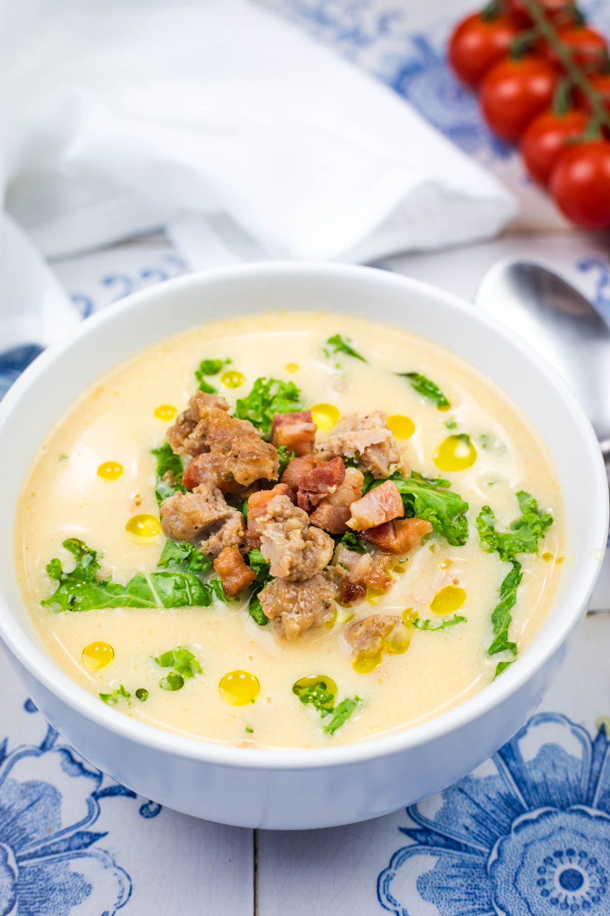 A white bowl of Creamy Tuscan Soup With Sausage & Kale.