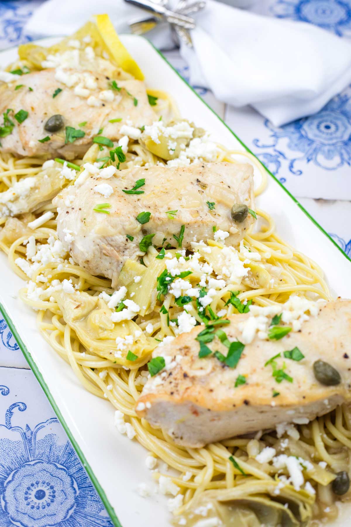 Skillet Chicken with Lemon, Artichokes, & Feta served on a white platter on the table.