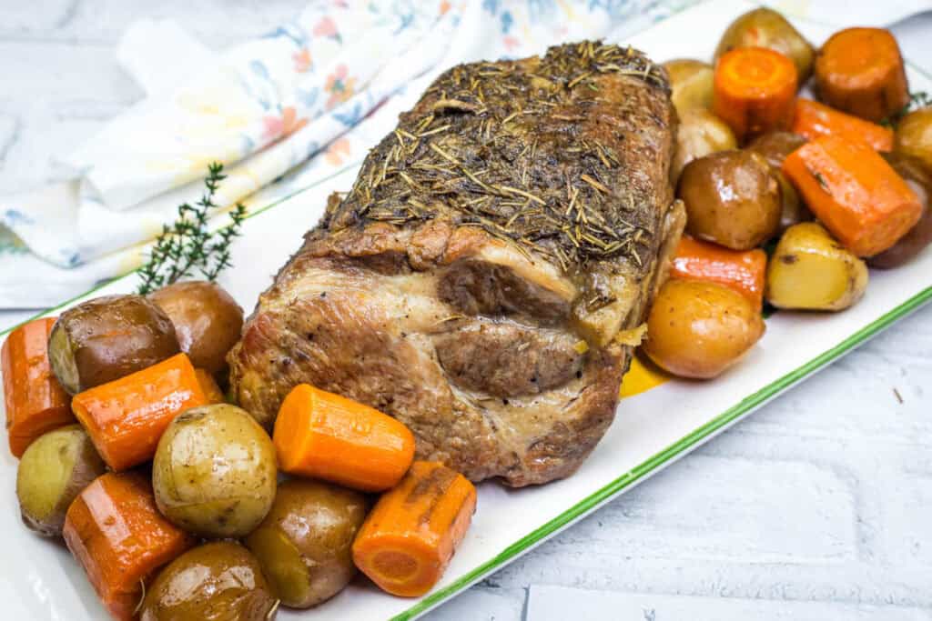 A plate with a Slow Cooker Herb-Crusted Pork Roast and roasted vegetables.