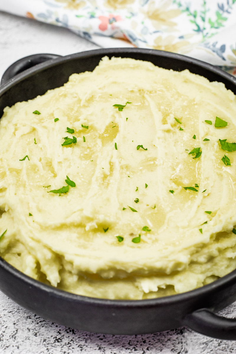 Creamy mashed potatoes topped with melted butter and garnished with fresh parsley.