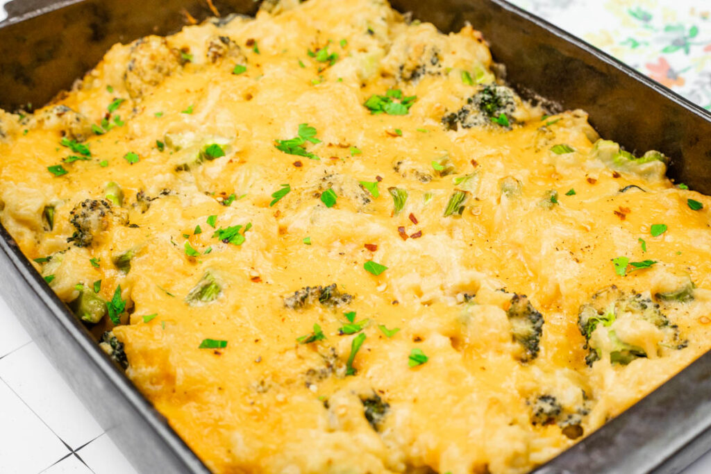 Cheesy Broccoli Rice Casserole with No Canned Soup in a baking dish, topped with melted cheese and garnished with chopped parsley.