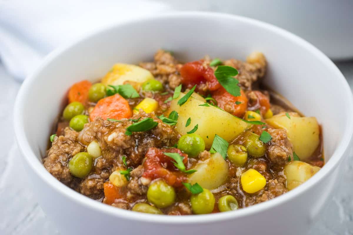 A white bowl filled with easy Hamburger stew garnished with parsley.