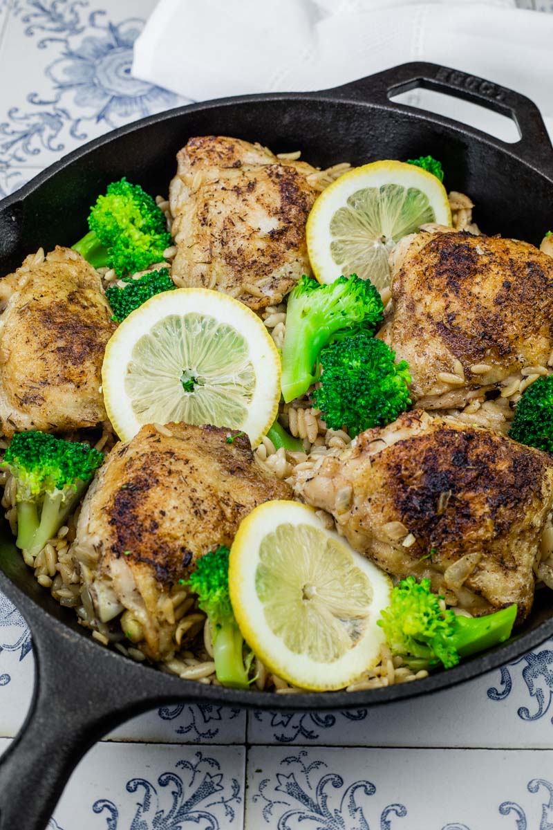 A black skillet with five pieces of Lemon Chicken Broccoli Orzo Skillet.
