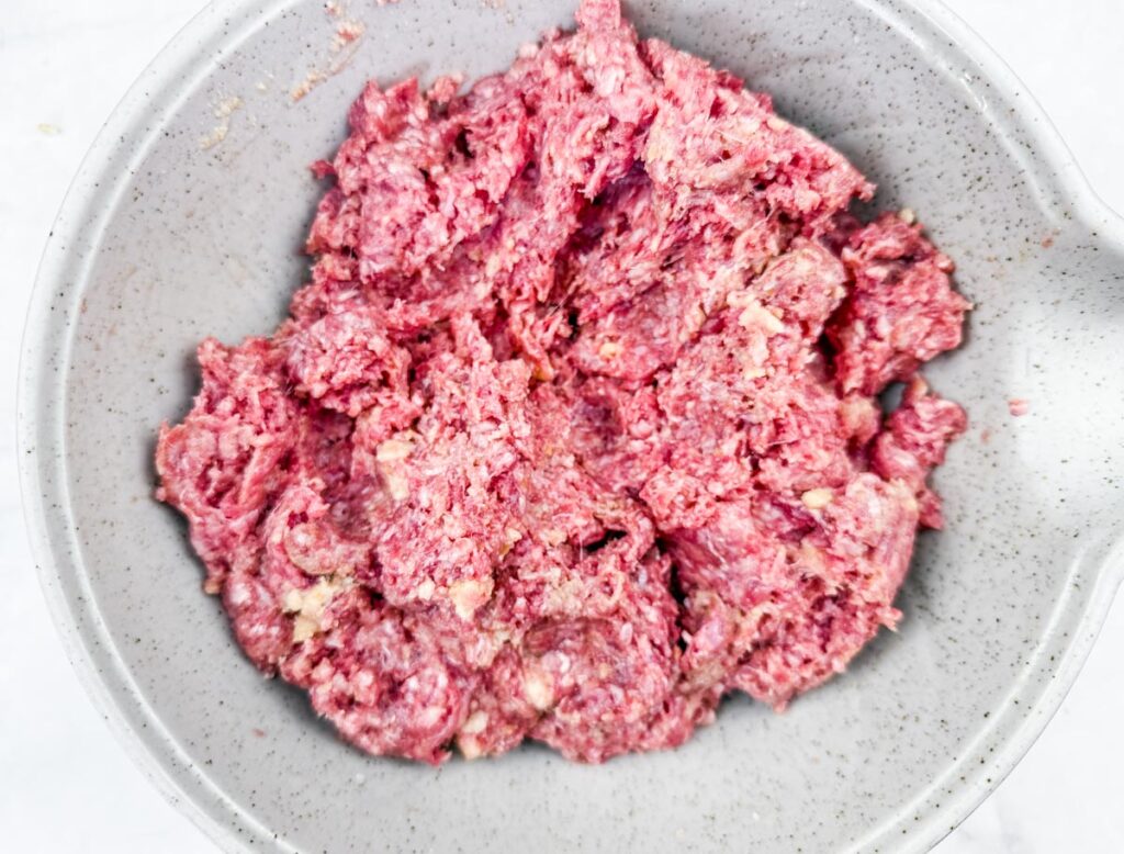 A bowl filled with raw ground meat.