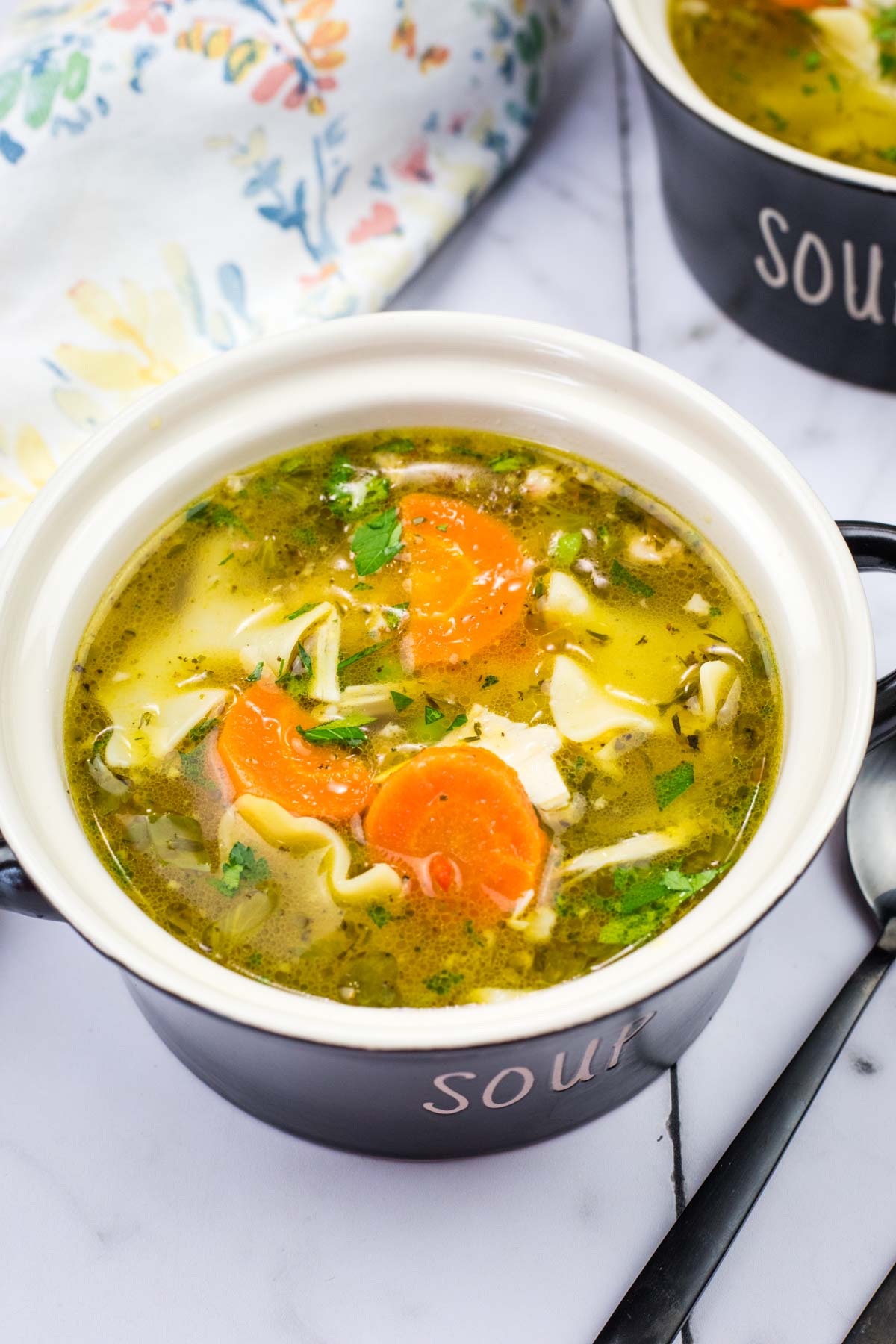 A bowl of Rotisserie Chicken Noodle Soup with a spoon beside it.