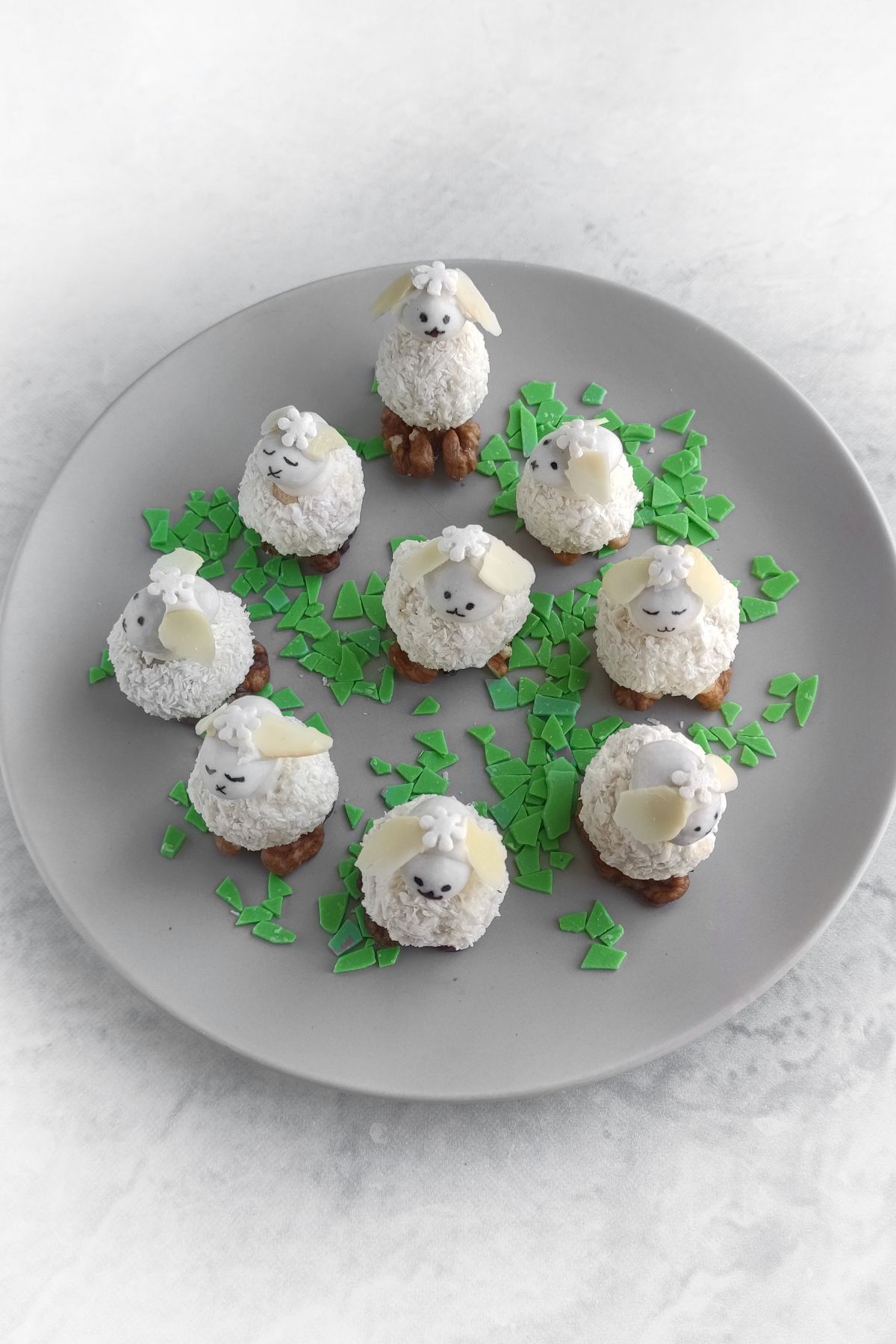 A plate of Easter Bunny Treats with almond ears and edible green garnish, arranged in a circle on a gray plate.