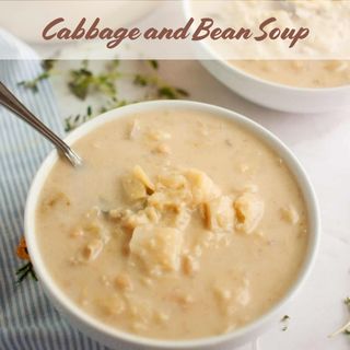Bowl of cabbage and bean soup with a spoon, on a striped cloth background.