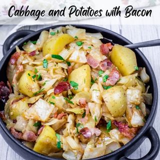 A black bowl filled with Cabbage & Potatoes with Bacon with a spoon on the side.