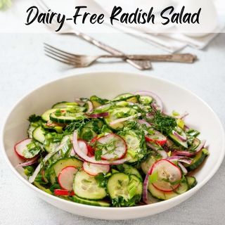 A bowl of dairy-free radish salad with cucumbers, red onions, and dill. Two forks are placed behind the bowl.