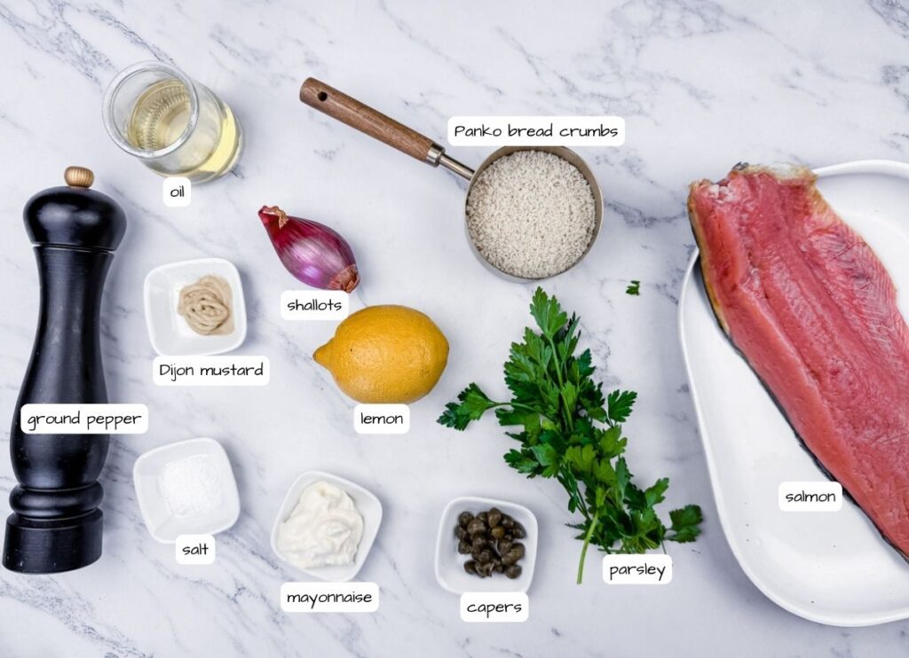 Ingredients on a counter: salmon, Panko bread crumbs, oil, shallots, Dijon mustard, lemon, parsley, mayo, capers, ground pepper, and salt.