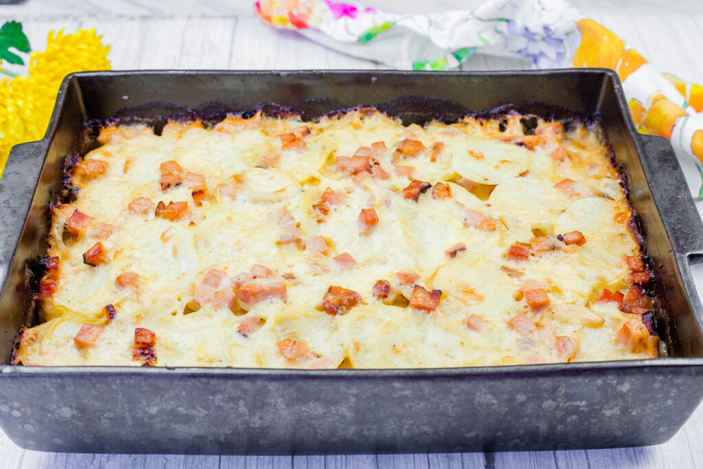 A baked dish of Scalloped Potatoes with Ham and Cheese in a rectangular pan.