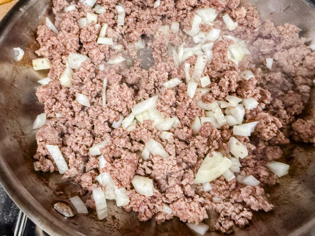 Ground meat and chopped onions cooking in a pan.