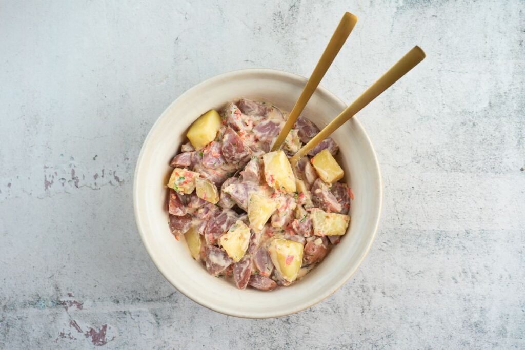 Mixing dressing with potatoes for Creamy Red Potato Salad with Pickle.