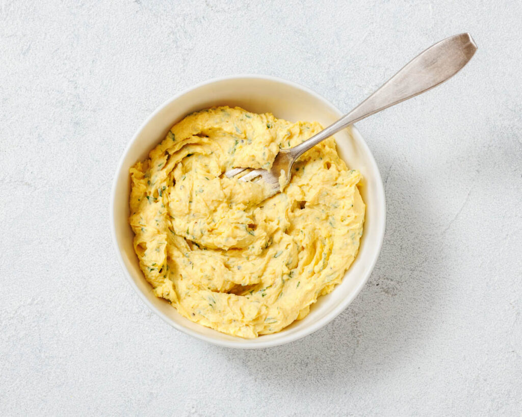 Overhead shot of deviled egg filling in a white bowl with a spoon.