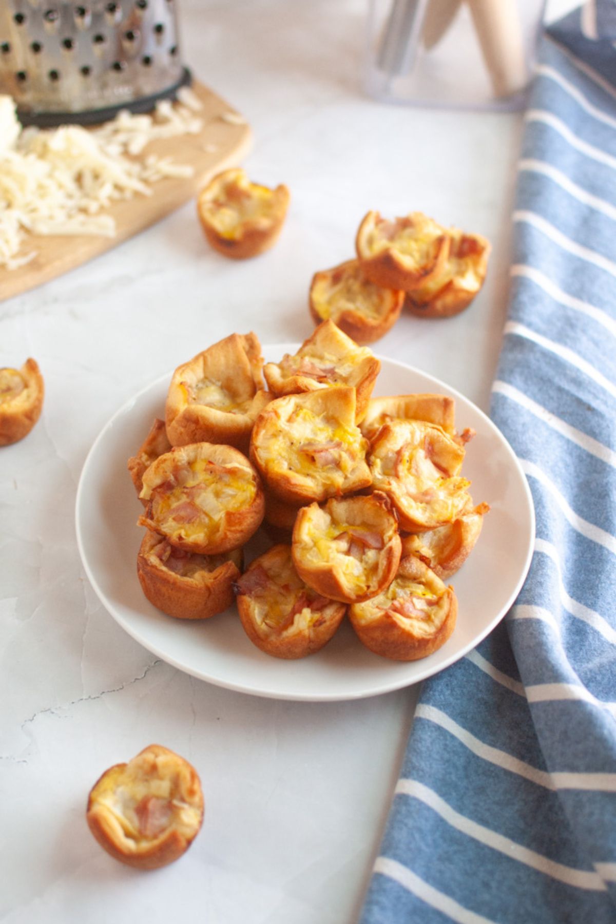 A white plate piled with small, golden-brown ham and cheese puffs.