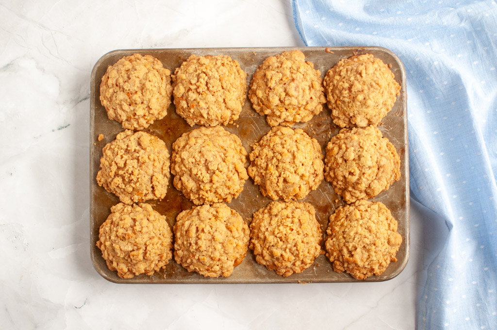 Overhead shot of a carrot muffin tin filled with twelve golden-brown maple oat muffins.