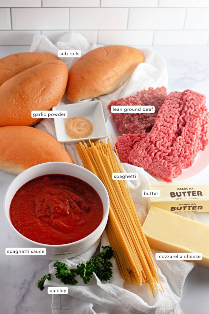Ingredients for a spaghetti sandwich recipe are displayed: sub rolls, garlic powder, lean ground beef, spaghetti, butter, mozzarella cheese, spaghetti sauce, and parsley.