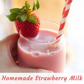 A glass of pink strawberry milk with a red and white striped straw, garnished with a fresh strawberry. Text at the bottom reads “Homemade Strawberry Milk.”.