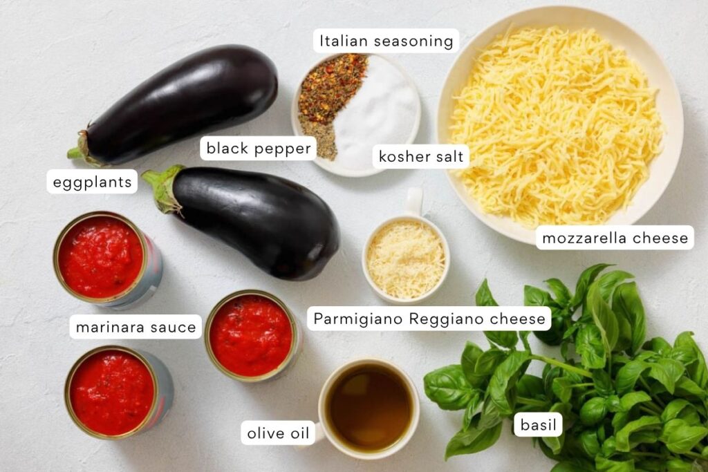 Ingredients for eggplant parmesan including two eggplants, marinara sauce, olive oil, basil, shredded mozzarella, Parmesan, Italian seasoning, kosher salt, and black pepper.