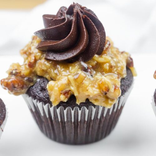 A close-up of German chocolate cupcakes topped with coconut-pecan frosting and a swirl of chocolate icing.