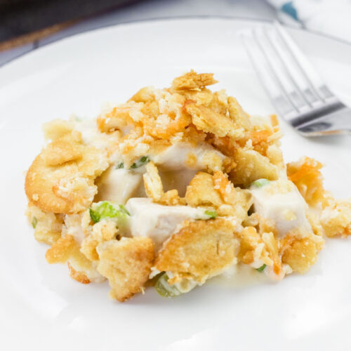 A serving of chicken casserole with cracker topping on a white plate, accompanied by a fork.