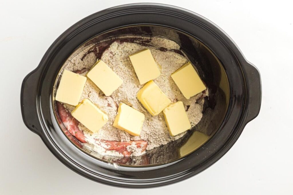 Butter chunks scattered across the top of the seasoned pork.