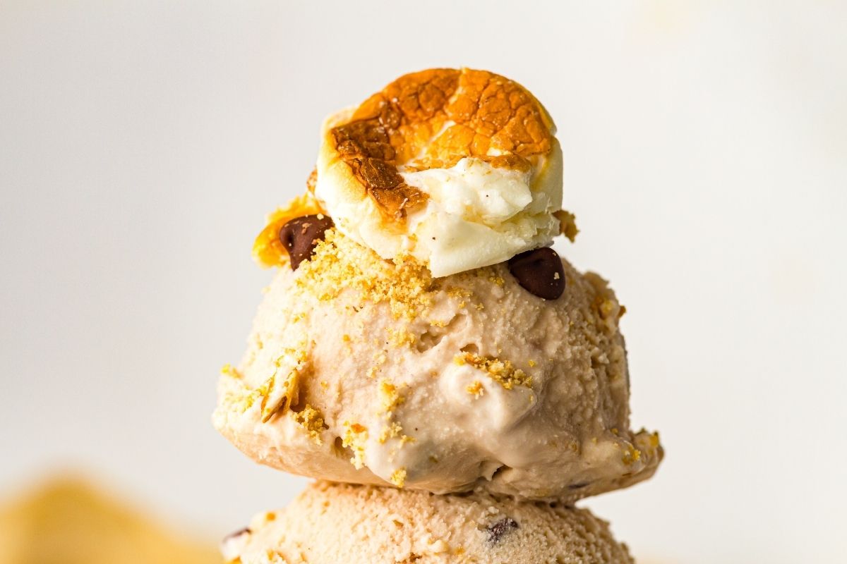A scoop of S&rsquo;mores  ice cream topped with crushed graham crackers, chocolate chips, and a toasted marshmallow.