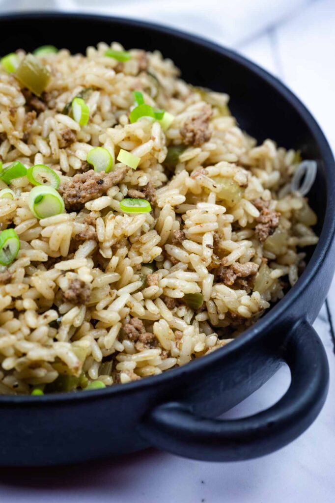 A black bowl filled with rice mixed with ground meat and topped with chopped green onions.