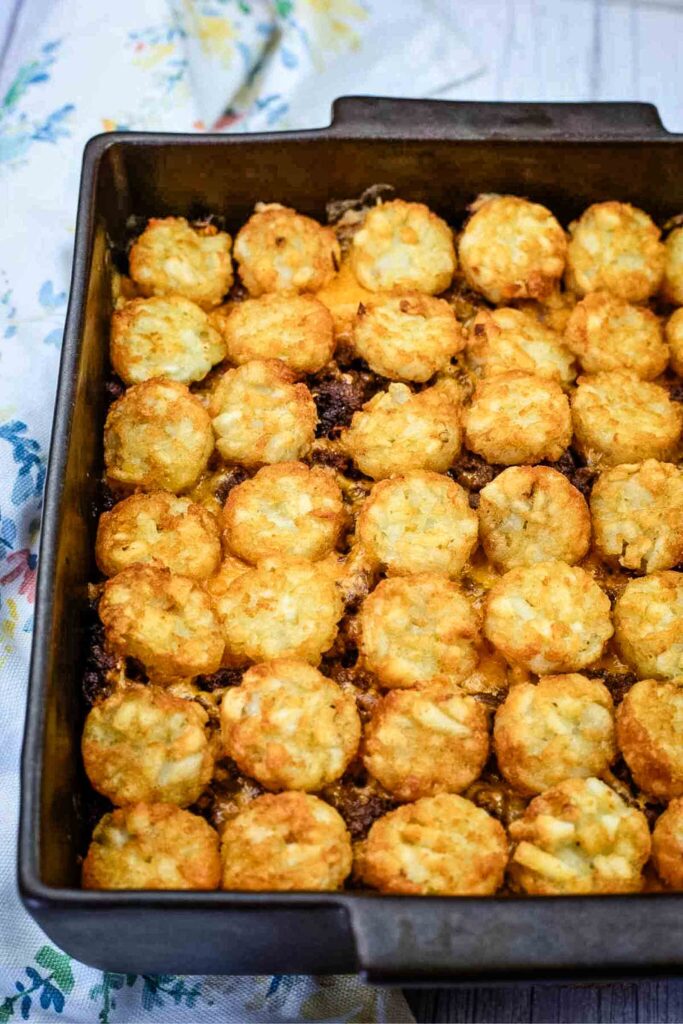 A rectangular baking dish filled with a casserole topped with rows of golden-brown tater tots.